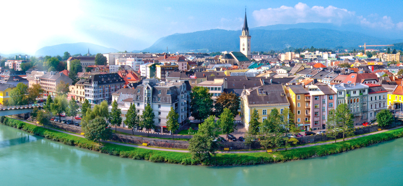Stadtansicht von Villach mit Blick auf Drau und Innenstadt mit Stadtpfarrturm an einem sonnigen Sommertag