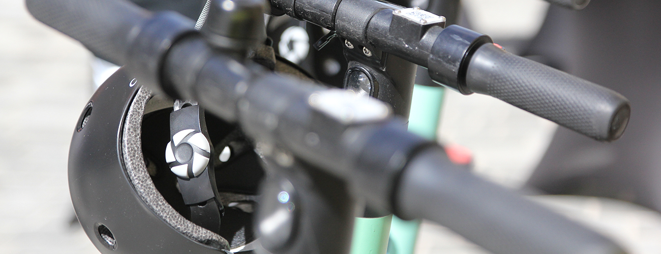 Lenkräder von 2 E-Scooter, ein Helm im Hintergrund