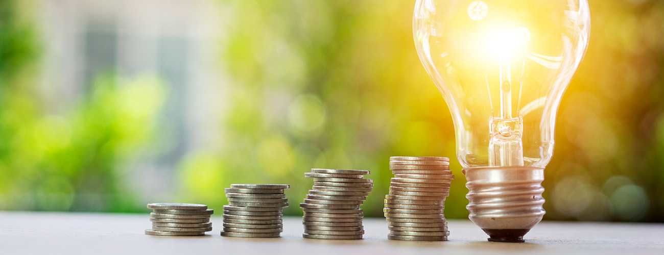 größer werdende Kleingeldstapel und Glühbirne