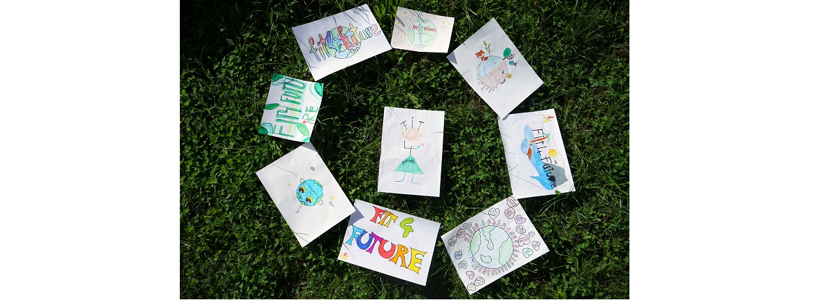 Zeichnungen von Schulkindern liegen ausgebreitet auf einer Wiese