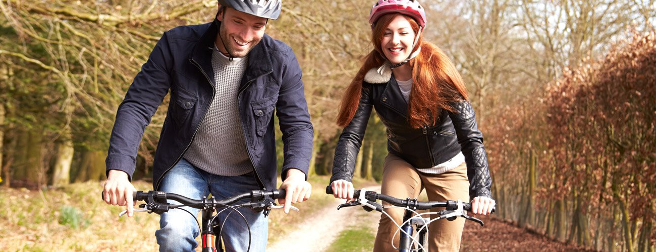 Mann und Frau beim Radfahren im Herbst auf Radweg mit Fahrradhelm