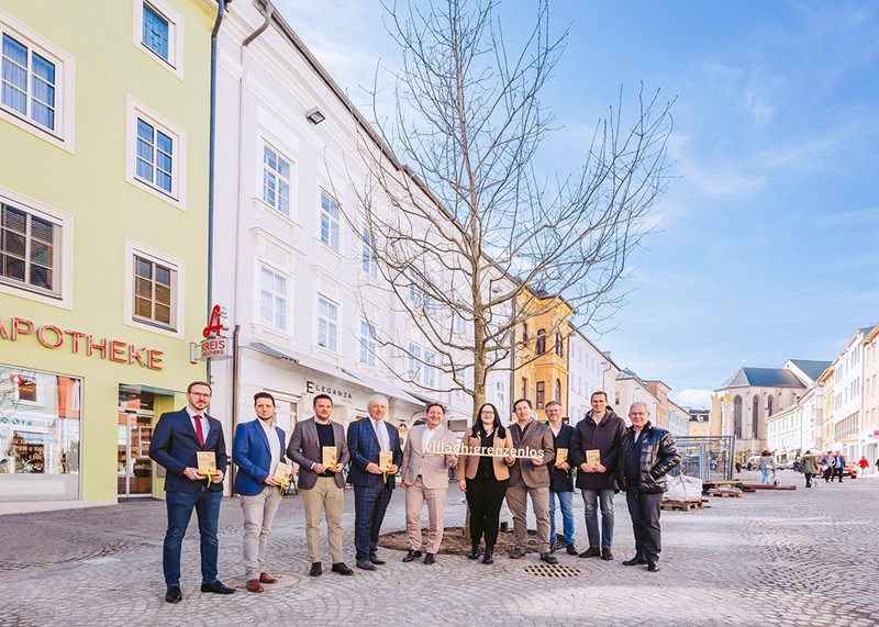 Bürgermeister Günther Albel, Vizebürgermeisterin Sarah Katholnig und Stadtrat Harald Sobe mit den Villacher Baumpaten vor dem ersten Baum auf dem Hauptplatz.